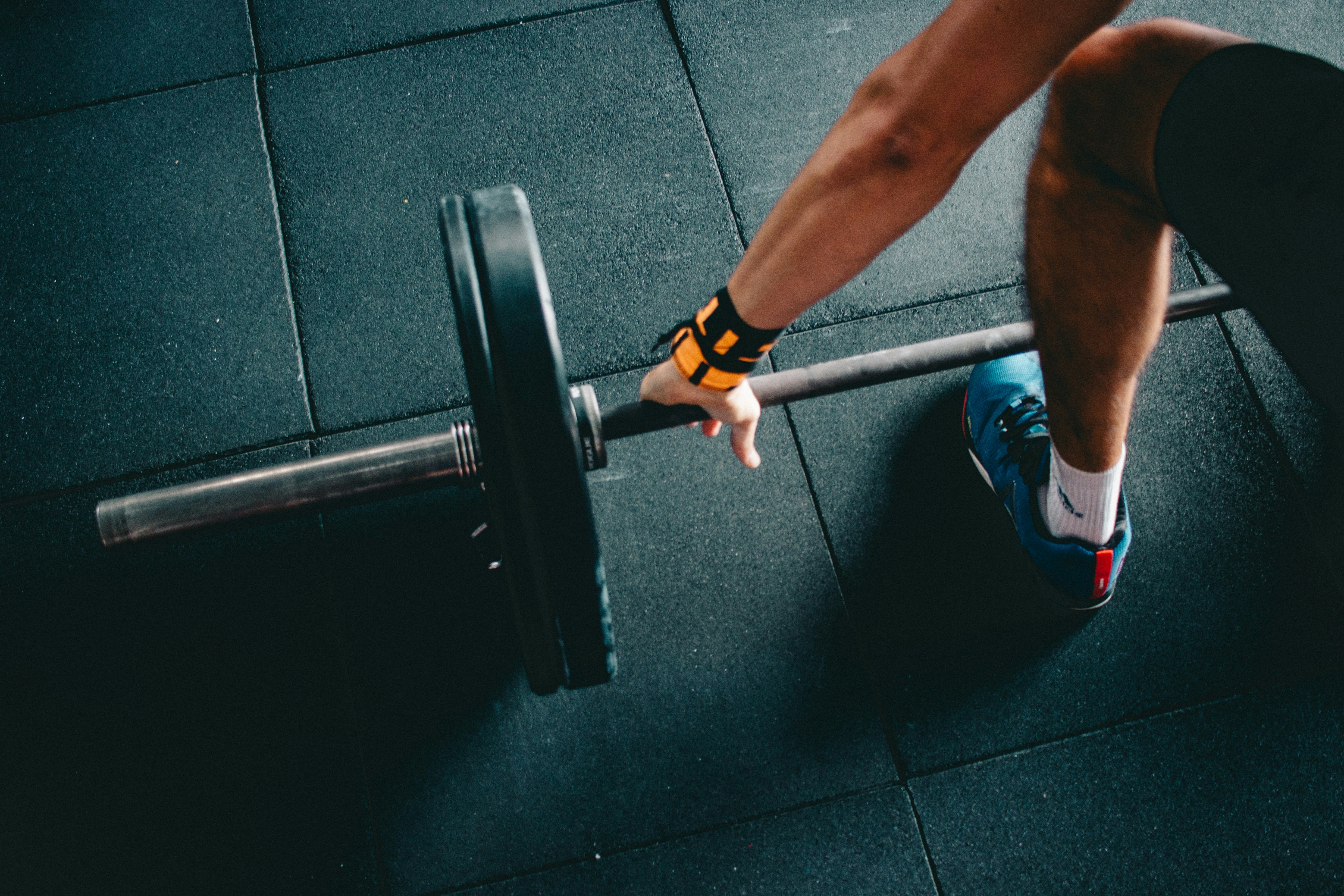 An athlete preparing a barbell for deadlift, representing structured strength training and the importance of focus in adapting workout routines.