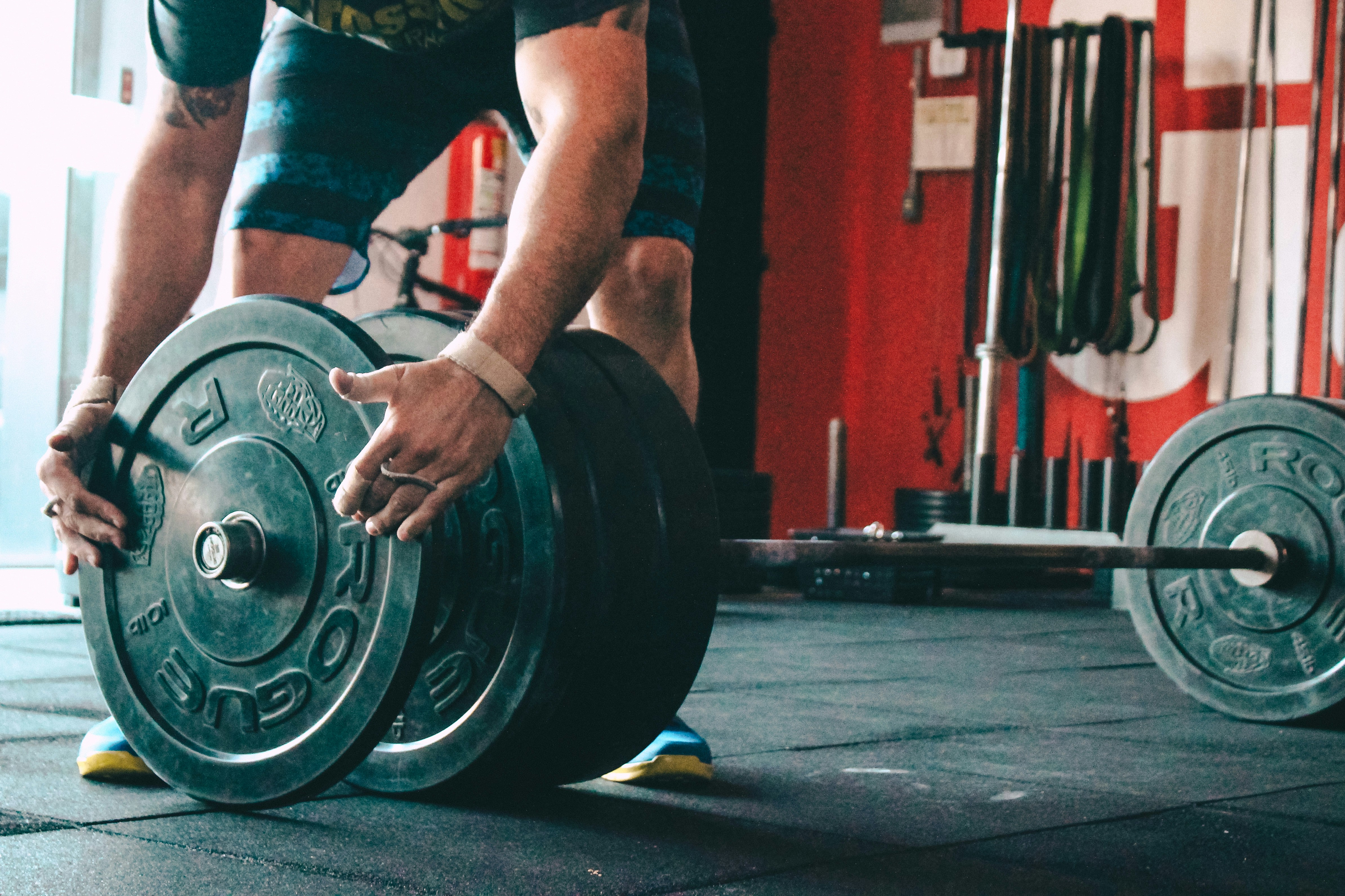 A weightlifter setting up plates on a barbell, highlighting the need for structured planning and focus in varied strength training routines.