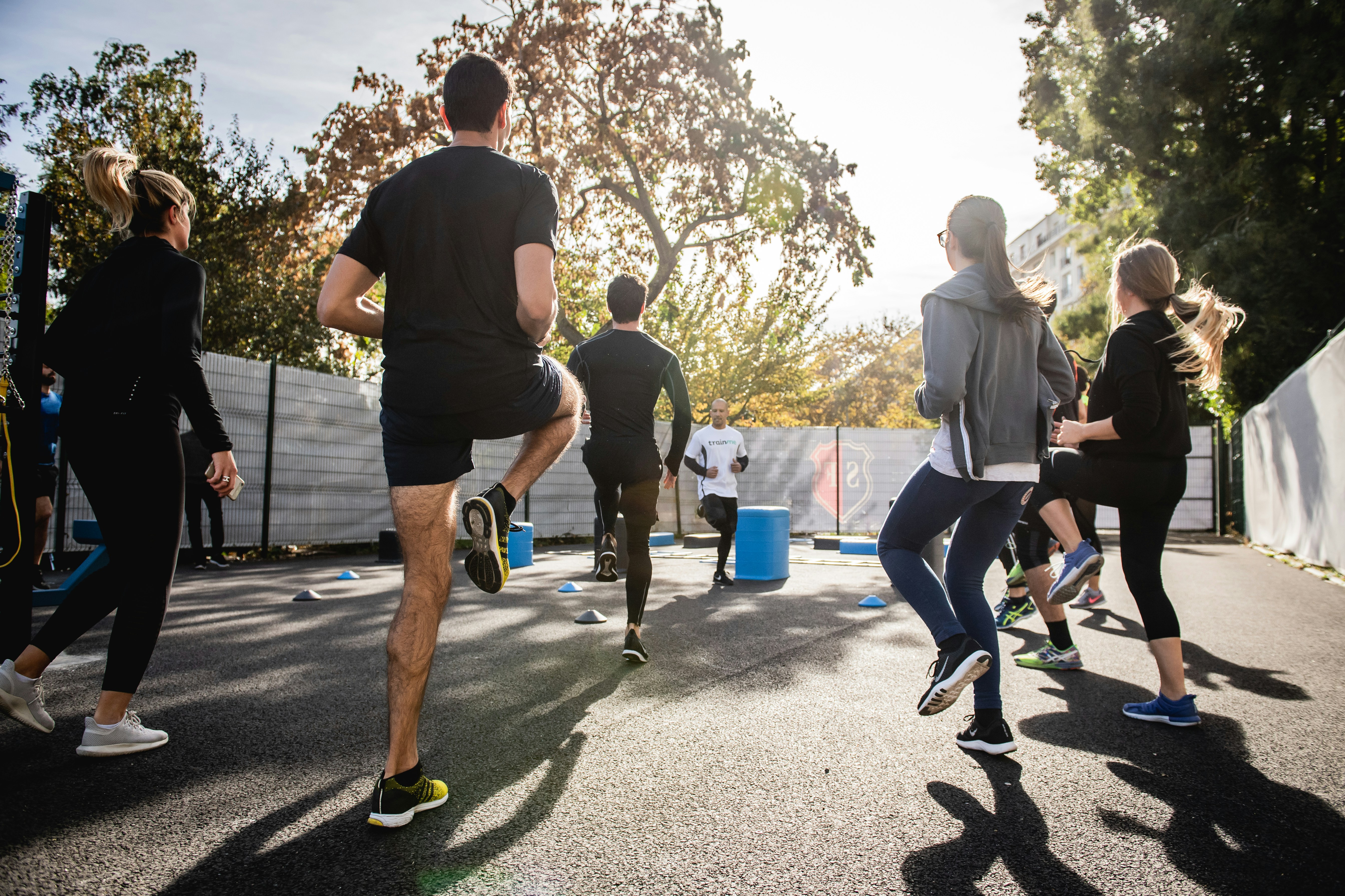 A group of athletes performing outdoor fitness exercises under the guidance of a coach, showcasing teamwork and motivation.